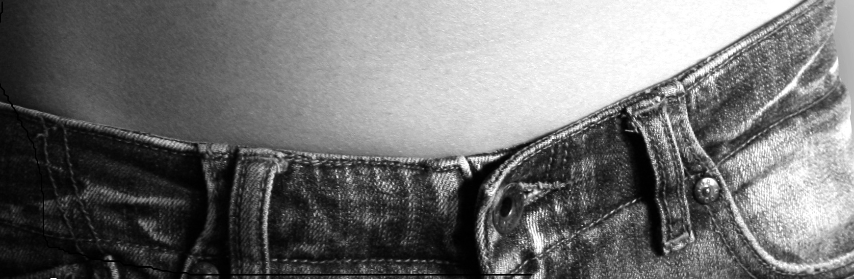 Imagen que muestra un pantalón vaquero abrochado y parte del abdomen de una persona