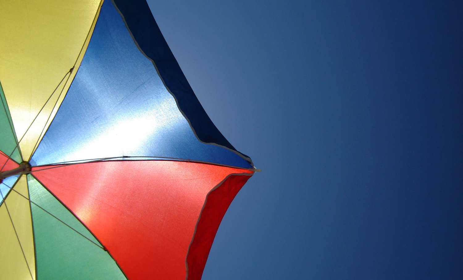 Imagen parcial de una sombrilla de colores en el cielo azul
