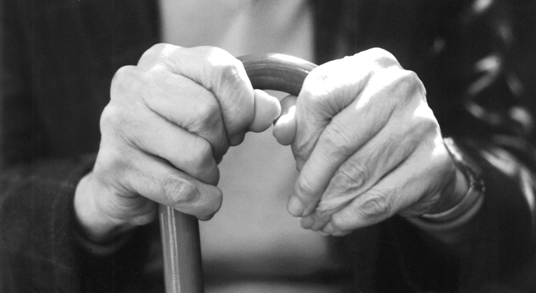 Imagen de las manos de un anciano apoyadas en un bastón