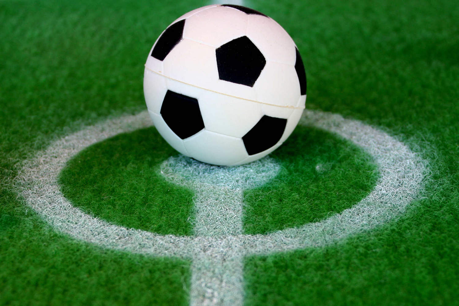 Imagen de una pelota de futbol en medio del círculo central de un campo de futbol