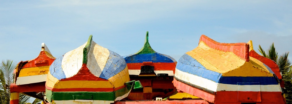 Imagen de barcas de colores reposando invertidas en la playa