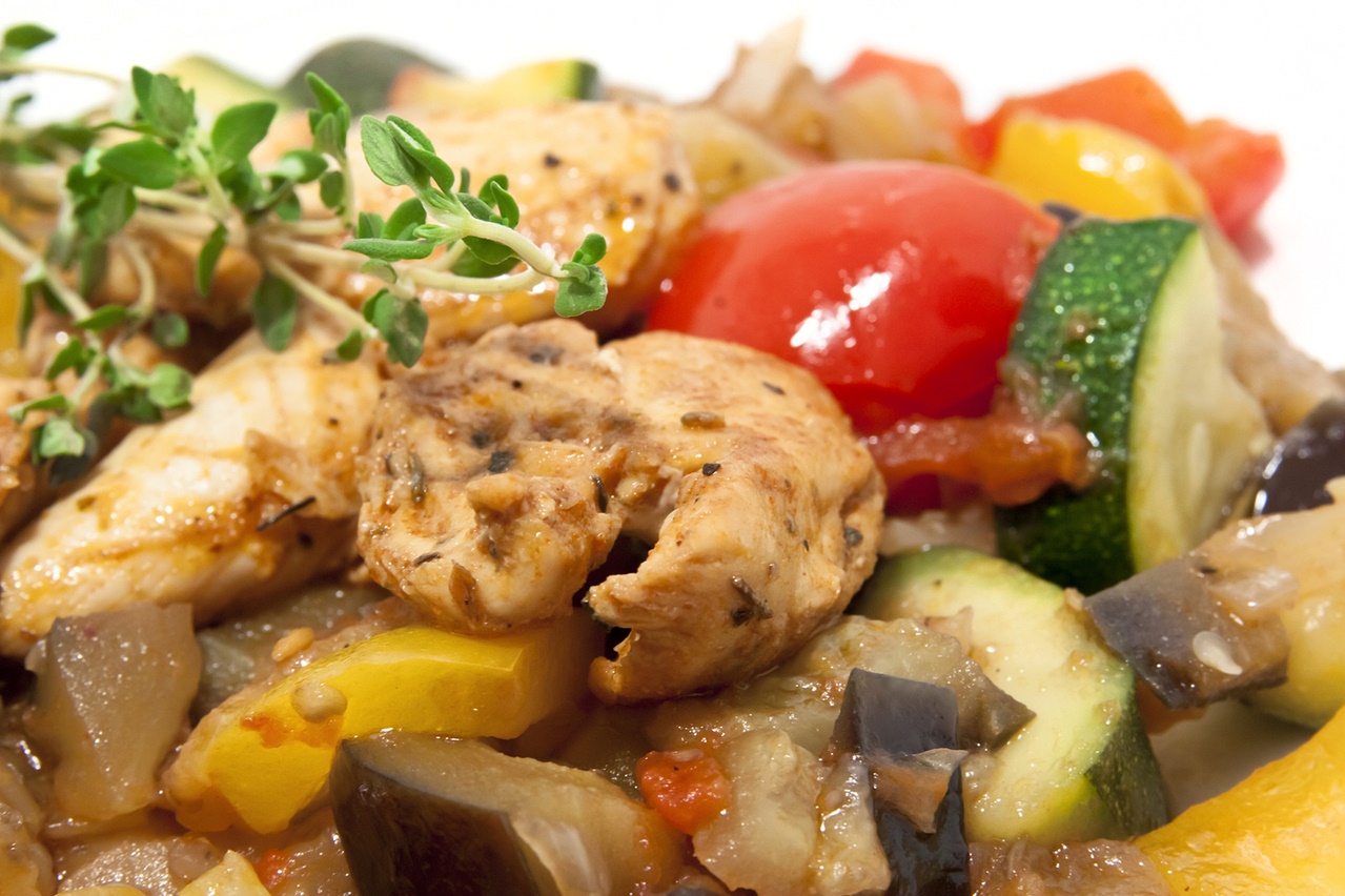 Imagen a color de un plato con pollo asado con verduras de colores vivos