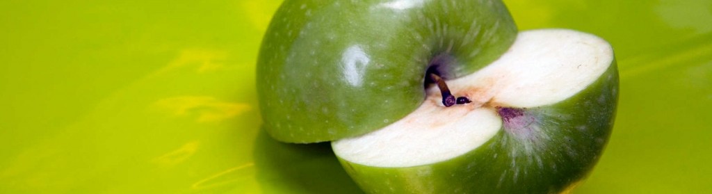 Imagen de manzana verde cortada a la mitad sobre fondo verde