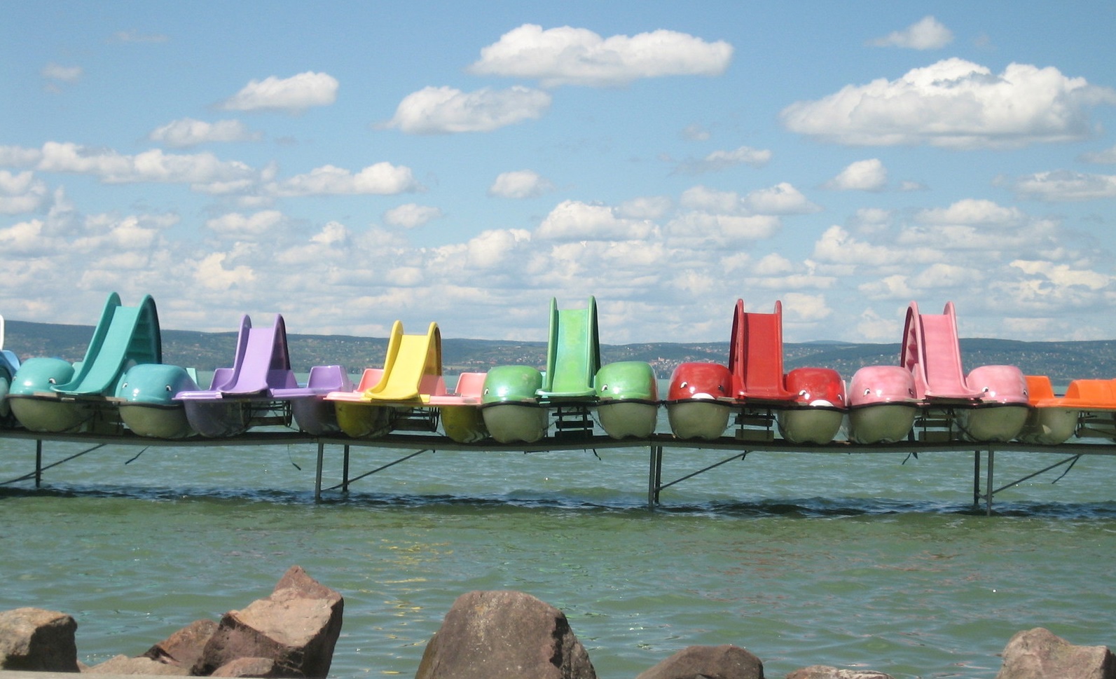 Imagen de barcas de colores apoyadas en un saliente de madera sobre el mar