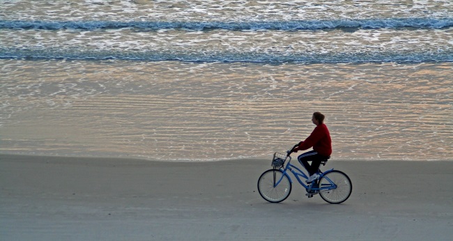 mujer paseando en bicicleta por la playa